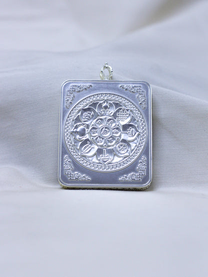 Backside side of ilver-toned pendant with engraved eight-auspicious symbols with decorative corner motifs.