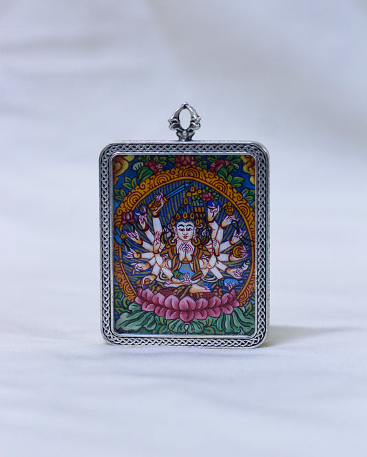 A square silver-toned pendant featuring a colorful Tibetan-style illustration of a multi-armed deity seated on a pink lotus, with a decorative silver border and top loop, shown against a white background.