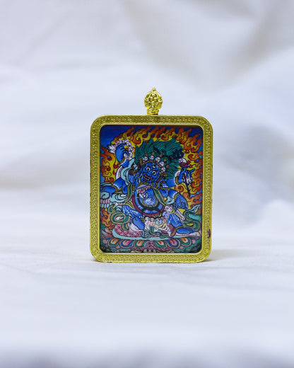 A Tibetan Buddhist Mahakala Thangka Pendant Necklace framed in ornate gold metal with a hanging loop of vajra at the top