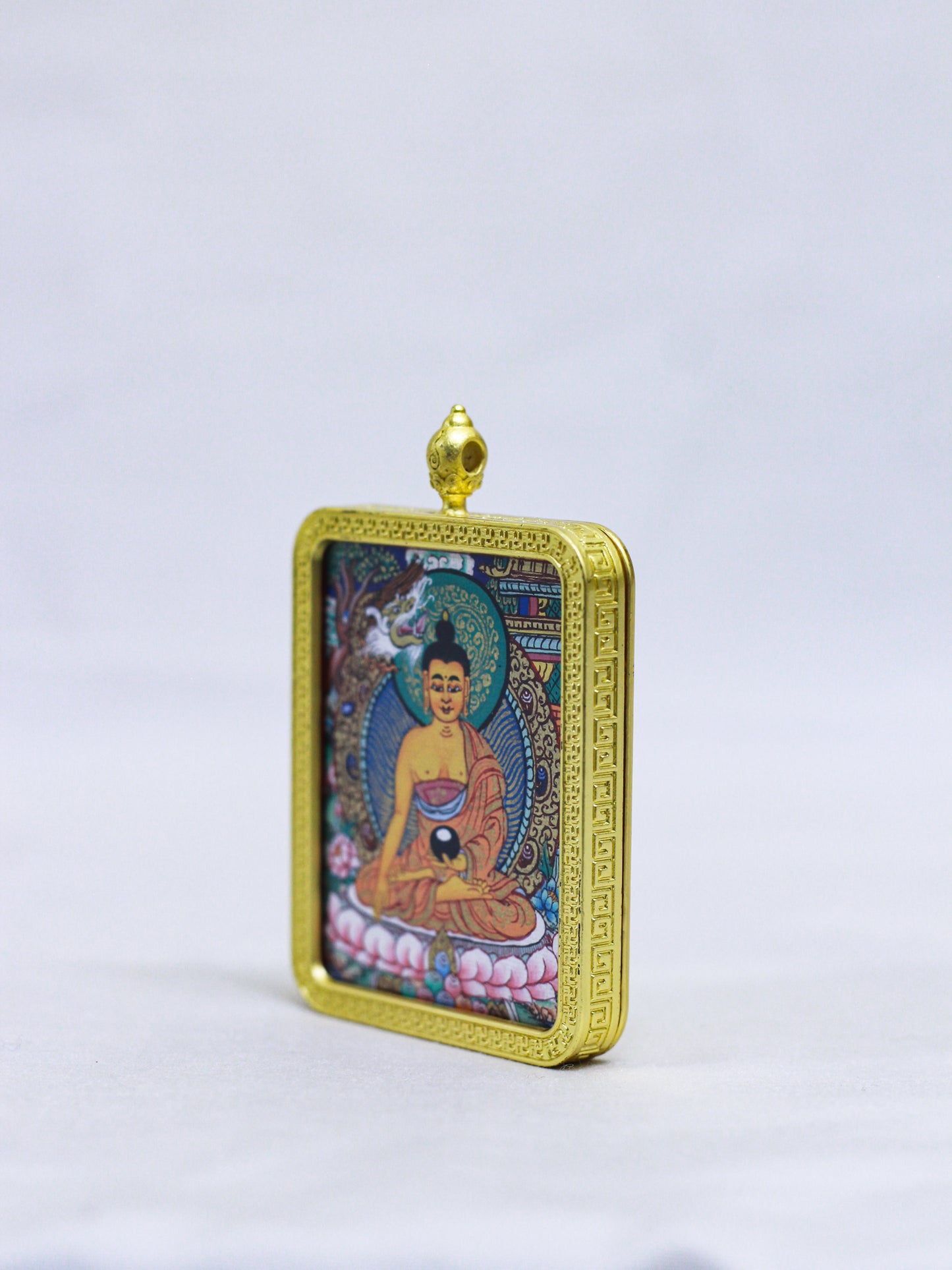 Side profile of the Shakyamuni Buddha butti thangka pendant showing the handcrafted gold locket design and dimensional frame.