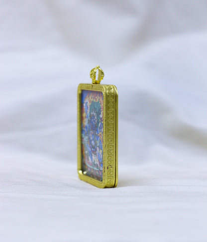 Side view of the Mahakala thangka pendant, a gold-toned border pendant with an embossed border standing upright 
