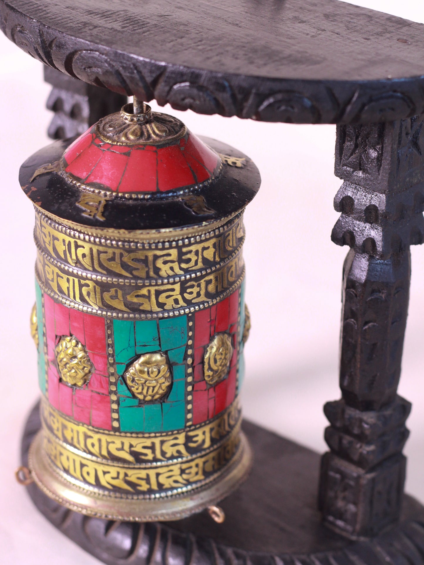 Side view of decorative tibetan prayer wheel featuring Tibetan inscriptions and colorful traditional craftmanship